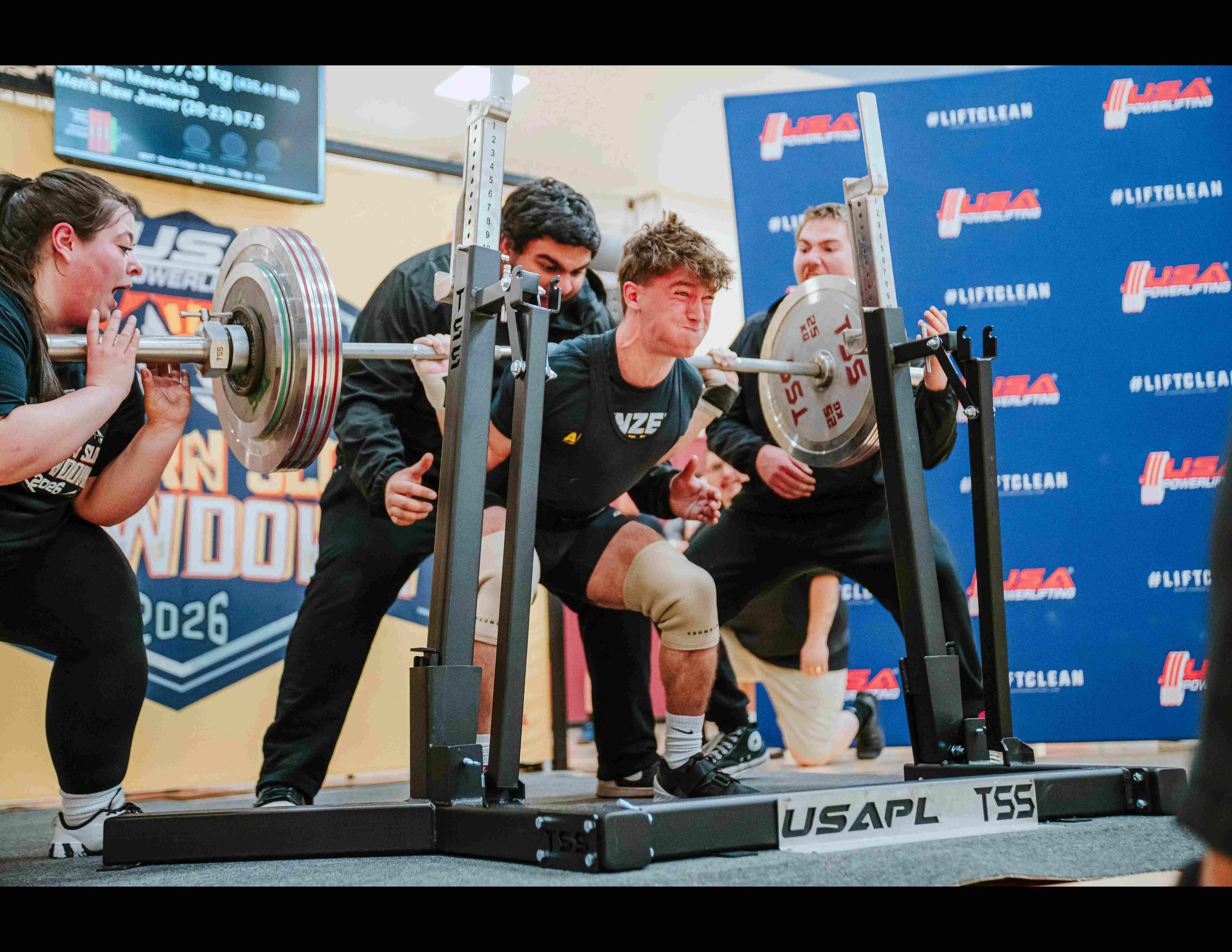 A Top Set athlete grinding through a heavy barbell squat with spotters at the Western Slope Showdown